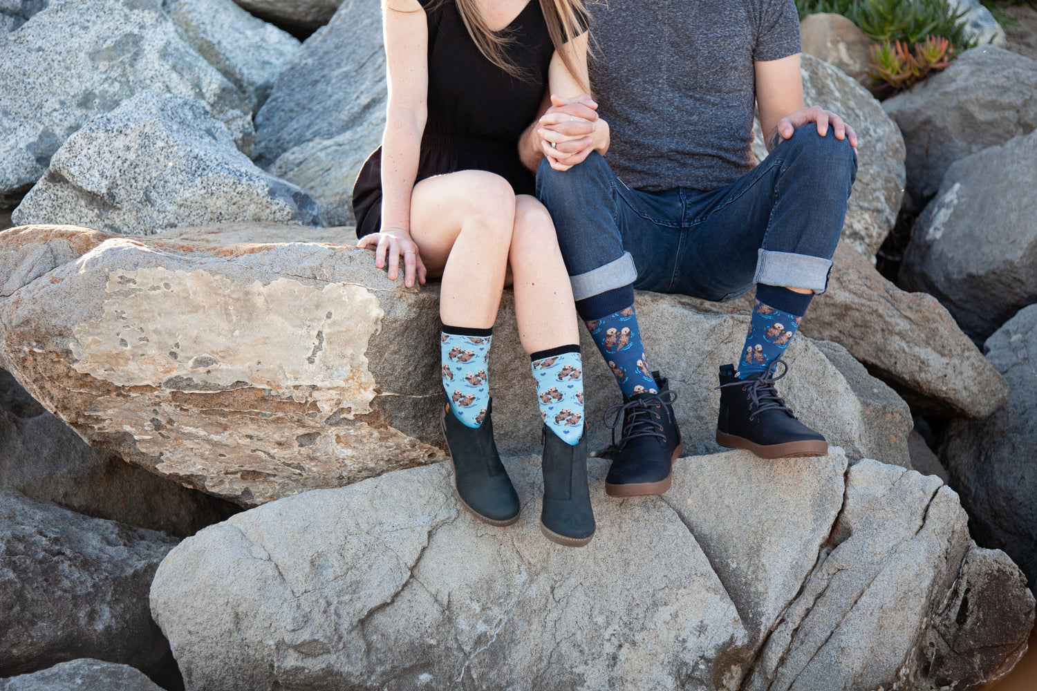 Photograph of a man and woman sitting on rocks while wearing Significant Otter socks